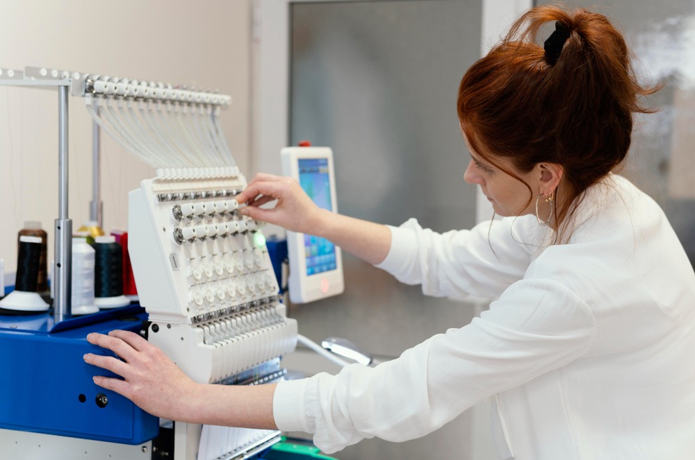 A woman handling a digital monogram embroidery machine